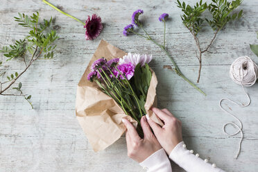 Hände einer Frau beim Einpacken eines Blumenstraußes - JUNF01336