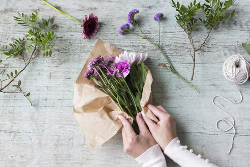 Hands of woman wrapping bunch of flowers - JUNF01336