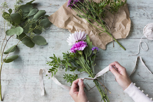 Woman's hand binding bunch of flowers - JUNF01337