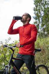 Athlete mountainbiking in nature, taking a break, drinking water - KKAF02367