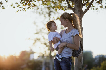 Mother holding her little son outdoors at sunset - AZOF00065