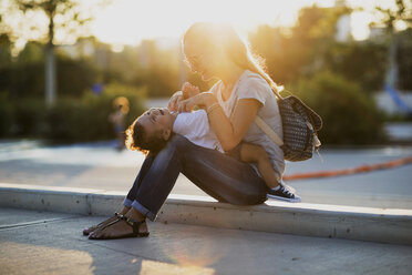 Glückliche Mutter spielt mit ihrem kleinen Sohn auf einem Platz bei Sonnenuntergang - AZOF00066
