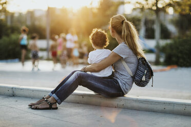 Mther sitting with her little son on a square at sunset - AZOF00068
