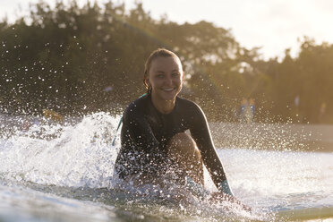 Junge Frau lächelt in die Kamera beim Surfen an der Küste, Kuta, Bali, Indonesien - AURF07619