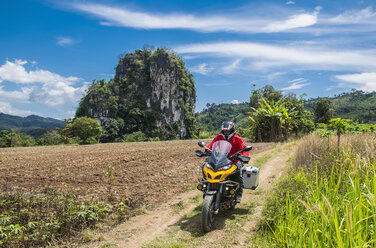 Mann fährt Motorrad auf unbefestigter Straße, Chiang Rai, Bezirk Mueang Chiang Rai, Thailand - AURF07655