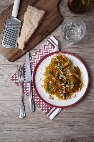 Teller mit Kürbisravioli mit Salbeiblättern, Parmesan und Pinienkernen, lizenzfreies Stockfoto