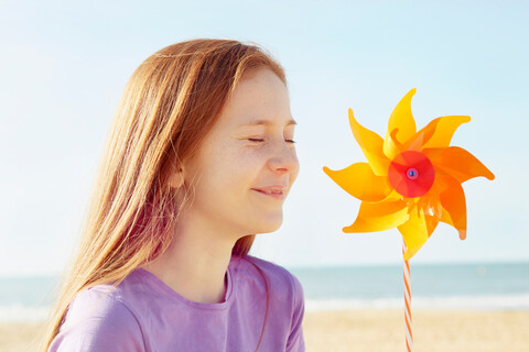 Mädchen mit Windrädern im Urlaub am Meer, lizenzfreies Stockfoto