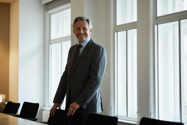 Portrait of businessman in office looking at camera smiling - CUF44007