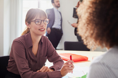 Businesswoman in office talking to colleague stock photo