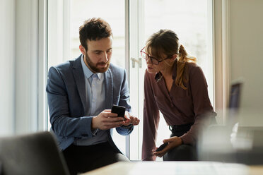 Kollegen im Büro schauen auf ihr Smartphone - CUF44035