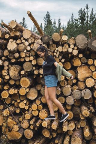 Happy young woman balancing on stack of wood stock photo
