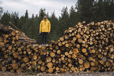 Man with camera standing on stack of wood stock photo