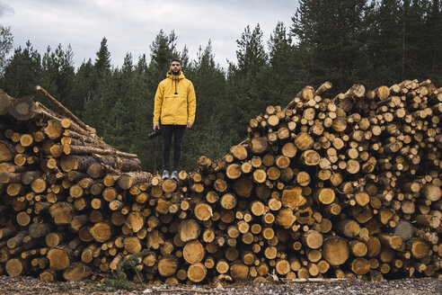 Mann mit Kamera auf einem Holzstapel stehend - KKAF02379