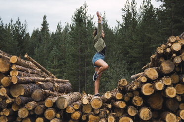 Junge Frau steht auf einem Bein auf einem Holzstapel - KKAF02383