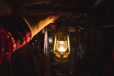 Hand holding storm lantern in a dark chamber - KKAF02405