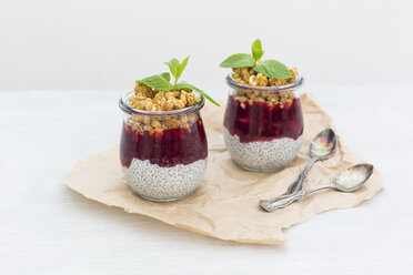 Zwei Gläser Chia-Pudding mit Kokosmilch, roter Grütze und Erdnuss-Granola-Topping - JUNF01359