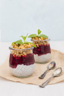 Zwei Gläser Chia-Pudding mit Kokosmilch, roter Grütze und Erdnuss-Granola-Topping - JUNF01360