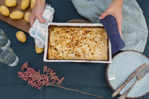 Woman serving potato mincemeat gratin, partial view - JUNF01362