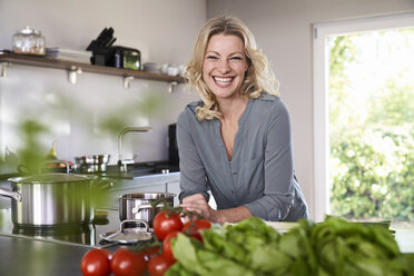 Porträt einer glücklichen Frau beim Kochen in der Küche - PDF01730