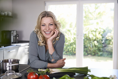 Porträt einer glücklichen Frau beim Kochen in der Küche, lizenzfreies Stockfoto