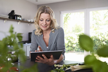 Smiling woman using tablet in kitchen - PDF01732