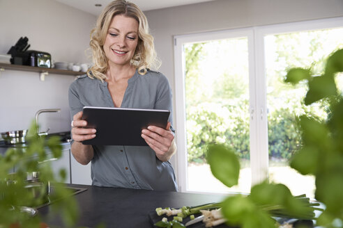 Lächelnde Frau mit Tablet in der Küche - PDF01733