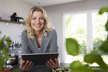 Lächelnde Frau mit Tablet in der Küche - PDF01734