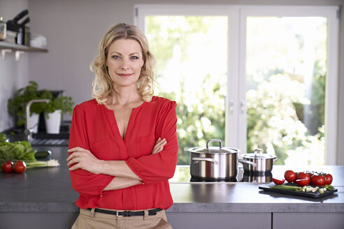 Porträt einer selbstbewussten Frau in roter Bluse, die in der Küche steht - PDF01745