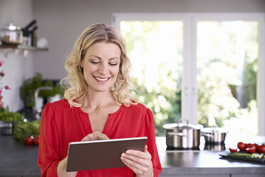 Lächelnde Frau mit Tablet in der Küche - PDF01748