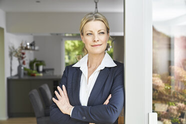 Portrait of confident businesswoman leaning against French door at home - PDF01768