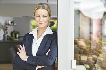 Portrait of confident businesswoman leaning against French door at home - PDF01769