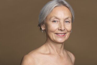 Portrait of naked senior woman in front of brown background - VGF00006