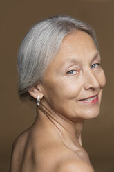 Portrait of naked senior woman with grey hair in front of brown background - VGF00007