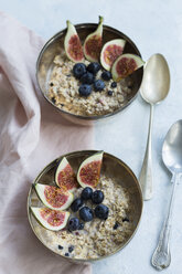 Two bowls of porridge with sliced figs, blueberries and dried berries - JUNF01385