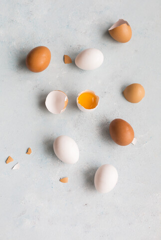 Ganze und geöffnete weiße und braune Eier auf hellem Grund, lizenzfreies Stockfoto