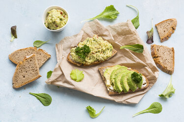 Brotscheiben mit geschnittener Avocado und Avocadocreme auf braunem Papier - JUNF01409