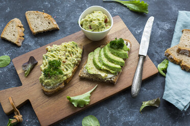 Brotscheiben mit geschnittener Avocado und Avocadocreme auf Holzbrett - JUNF01410