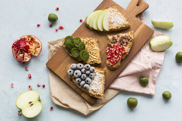 Bread slices with various toppings on wooden board - JUNF01415