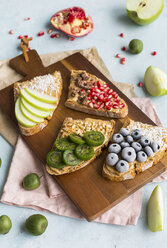 Bread slices with various toppings on wooden board - JUNF01416