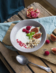 Bowl of natural yoghurt with fruit muesli, raspberries, figs and pomegranate seed - JUNF01429