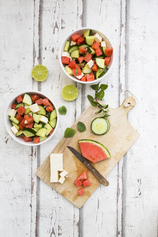 Wassermelonensalat mit Feta, Gurke, Minze und Limettendressing auf weißem Holz, lizenzfreies Stockfoto