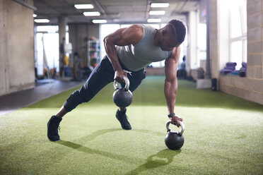 Mann macht Planke mit Kettlebells im Fitnessstudio - CUF44252