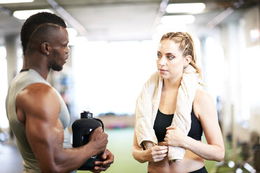 Trainer and female client talking in gym - CUF44271