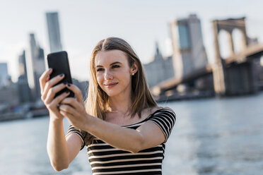 USA, New York, Brooklyn, Porträt einer jungen Frau, die ein Selfie mit ihrem Smartphone macht - GIOF04562