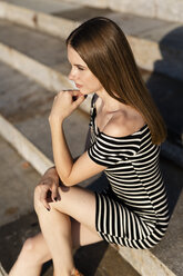 Young woman sitting on stairs at sunset - GIOF04564