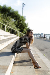 USA, New York, Brooklyn, young woman relaxing on stairs enjoying sunset - GIOF04566