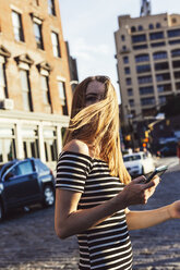 USA, New York, Brooklyn, Dumbo, Frau mit Mobiltelefon beim Überqueren der Straße - GIOF04578