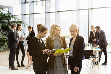 Geschäftsfrauen im Atrium des Büros mit digitaler Tafel - CUF44324