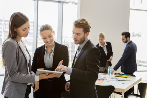 Businesswomen and man in office meeting using digital tablet - CUF44325