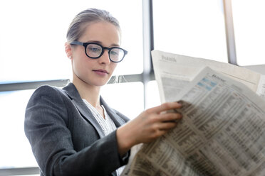 Businesswoman reading newspaper in office - CUF44338